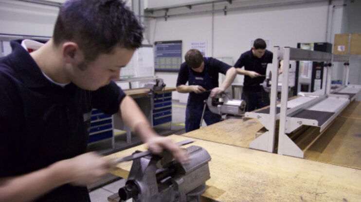 Drei Lehrlinge lernen das Feilen von Metall im Ausbildungszentrum bei weba Werkzeugbau in Dietach